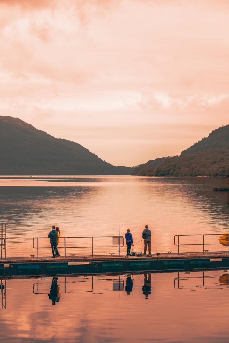 Serene view of people enjoying a sunset by the lake, reflecting a calm mood.